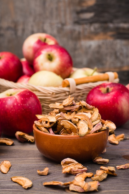 Gesneden gedroogde appels klaar om te eten in een kom en verse appels op een houten tafel