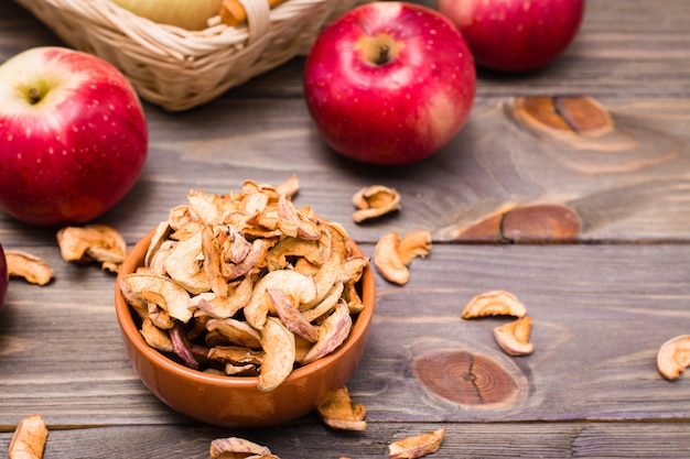 Gesneden gedroogde appels klaar om te eten in een kom en verse appels op een houten tafel