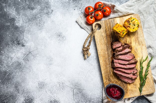 Gesneden gegrilde filet Mignon steak op een houten snijplank. Ossenhaas. Grijze achtergrond. Bovenaanzicht. Ruimte voor tekst