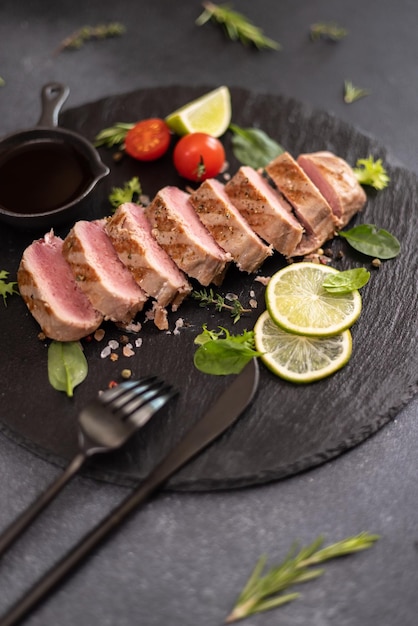 Gesneden gegrilde gekookte stuk tonijnfilet op een serveerbord van zwarte steen