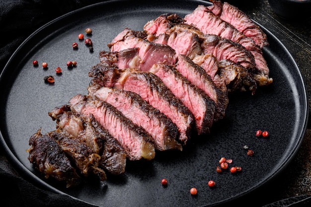 Gesneden gegrilde rib eye biefstuk rundvlees gemarmerd zeldzaam op plaat op oude donkere rustieke achtergrond