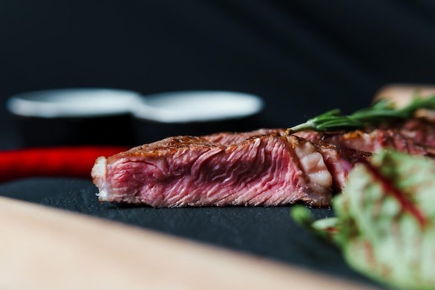 Gesneden gegrilde steak medium rare geserveerd op zwarte snijplank met groenten