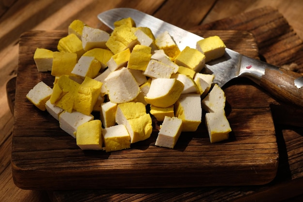 gesneden gele tofu op een snijplank van teakhout. roestvrijstalen mes. soja producten. tahoe.