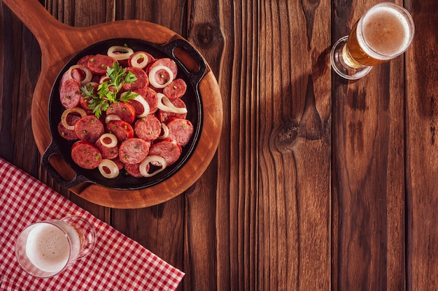 Gesneden gerookte gebakken calabrese worst, ui en bier - Braziliaans voorgerecht bovenaanzicht met kopie ruimte