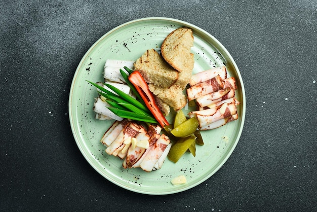 Gesneden gezouten reuzel met bruin brood en groenten Oekraïense traditionele gerechten op een bord Restaurant serveert close-up op een donkere stenen achtergrond