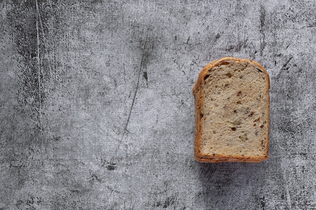 Gesneden graan volkoren brood op donkere rustieke houten achtergrond, bio ingrediënten, gezonde voeding, bovenaanzicht.