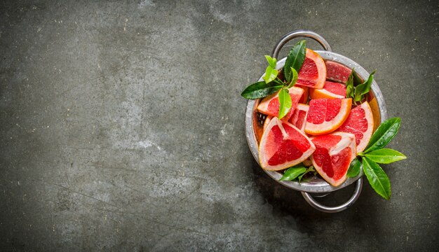 gesneden grapefruit met bladeren in een pan op stenen tafel. Bovenaanzicht