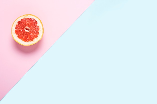 Gesneden grapefruit op een roze en blauwe achtergrond.