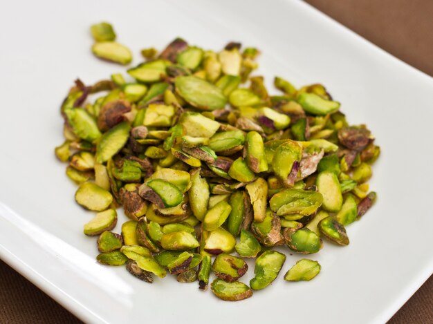 Foto gesneden groene pistachenoten op een witte plaat