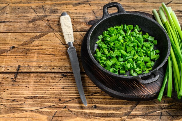 Gesneden Groene uien in een pan. Houten tafel. Bovenaanzicht.