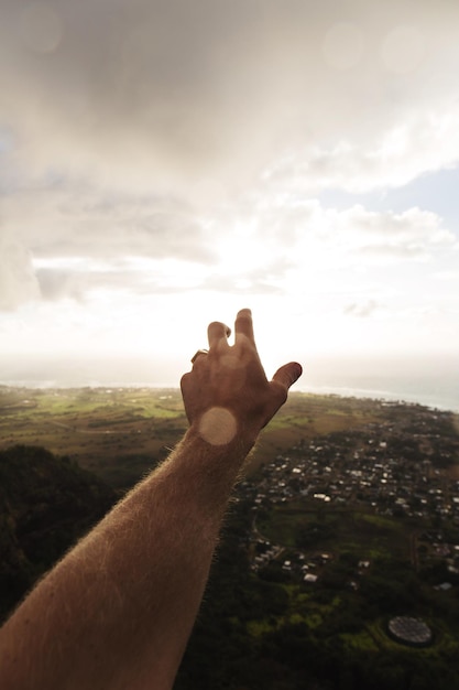 Foto gesneden hand van een man die tegen een bewolkte hemel gebaar maakt.