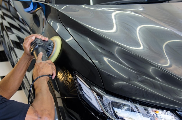 Gesneden hand van een persoon die een auto polijst in de garage