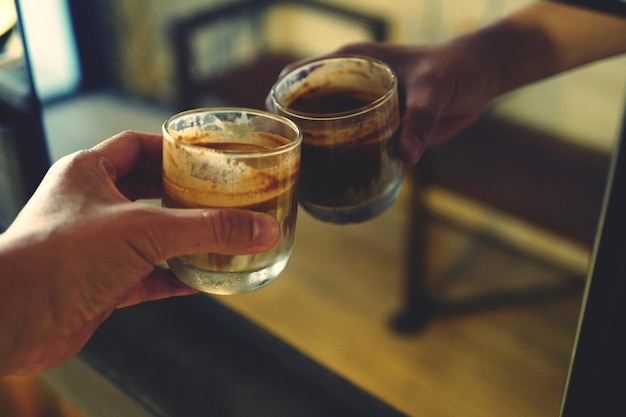 Gesneden hand van een persoon die een drankje tegen een spiegel houdt