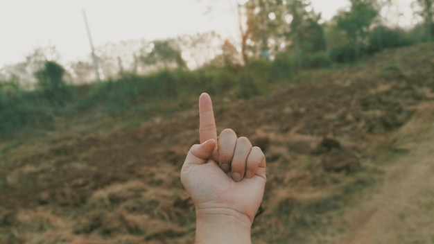 Foto gesneden hand van een persoon die tegen een heuvel gebaar doet