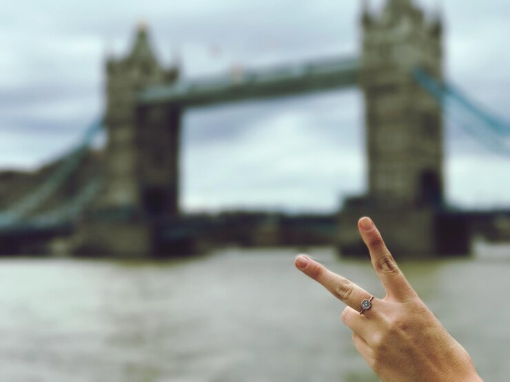 Foto gesneden hand van een vrouw die een vredesteken maakt tegen een brug in de stad