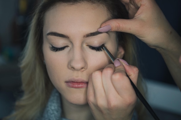 Gesneden hand van een vrouw die mascara aanbrengt op een vriend