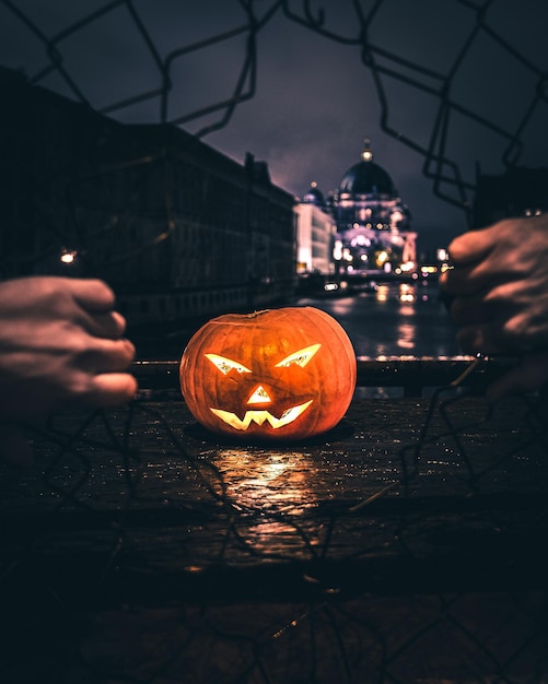 Gesneden handen breken het hek tegen de verlichte jack o lantaarn in de stad's nachts