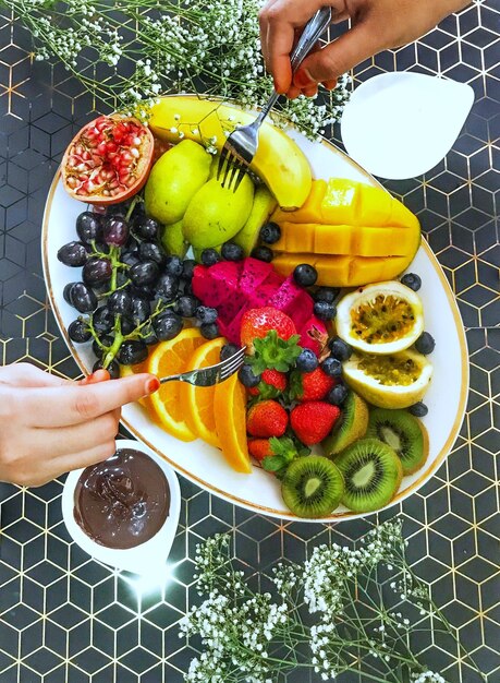 Gesneden handen met fruit van het bord op de tafel