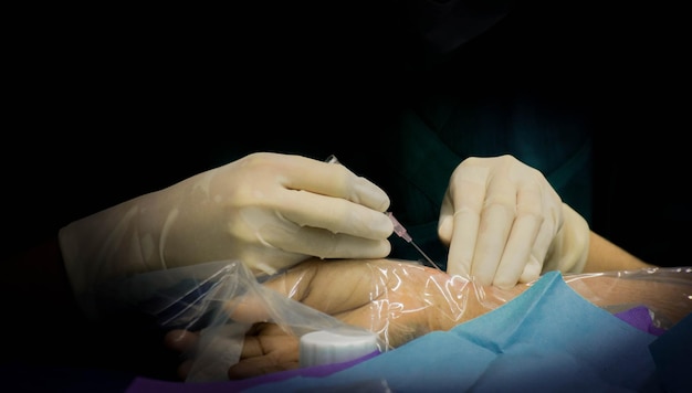 Gesneden handen van een arts die een patiënt injecteert tegen een zwarte achtergrond