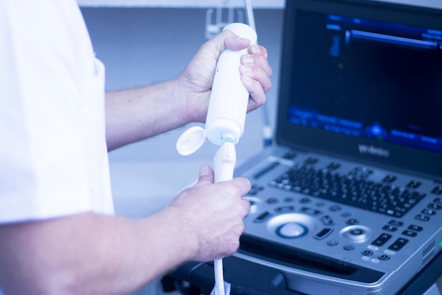 Foto gesneden handen van een chirurg die medische apparatuur vasthoudt in de operatiekamer