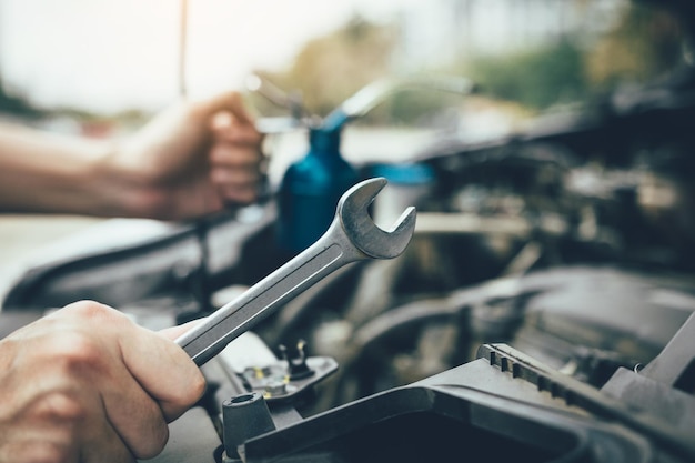 Gesneden handen van een mannelijke monteur die een auto repareert in de garage