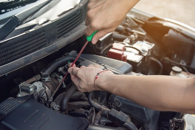 Gesneden handen van een monteur die een auto-motor repareert