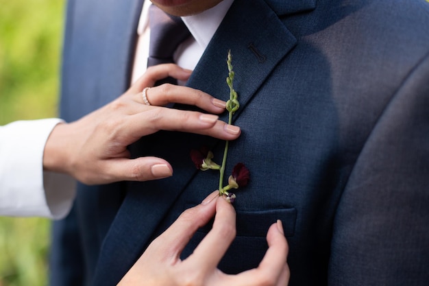 Foto gesneden handen van een vrouw die de boutonnière van de bruidegom aanpast