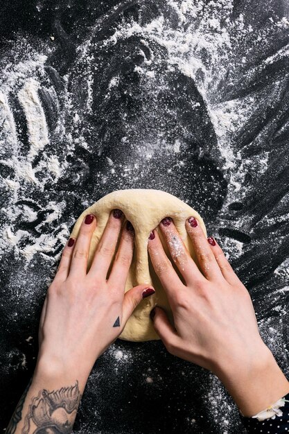 Gesneden handen van een vrouw die deeg in de keuken kneden