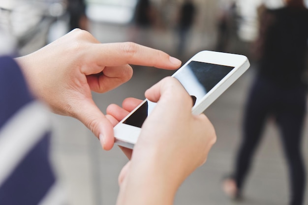 Gesneden handen van een vrouw die een telefoon gebruikt.