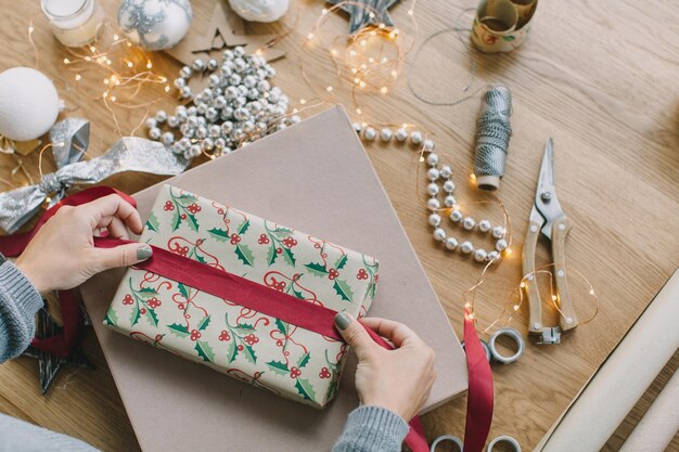 Foto gesneden handen van een vrouw die geschenken inpakt op tafel thuis