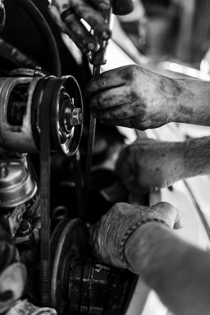 Foto gesneden handen van mensen die de motor van een auto repareren