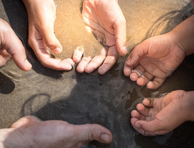 Gesneden handen van mensen op het strand.