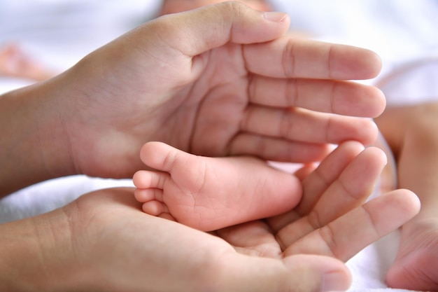 Foto gesneden handen van moeder die babyvoet vasthoudt