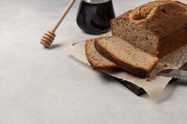 Gesneden kant-en-klaar bananenbrood met honing op witte plaat