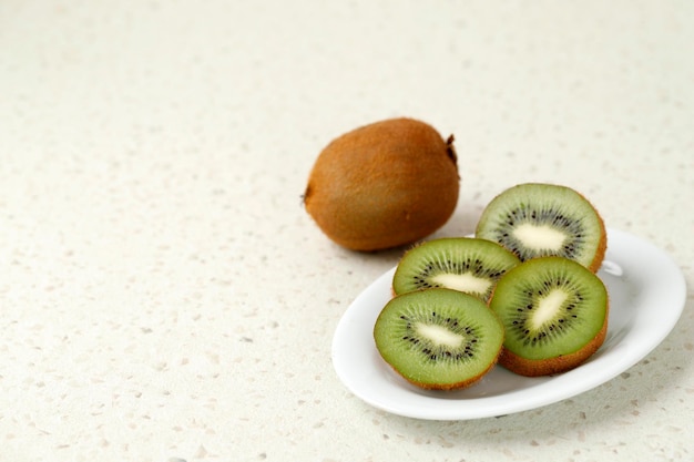 Gesneden Kiwi op witte plaat op marmeren spikkeltafel geïsoleerd