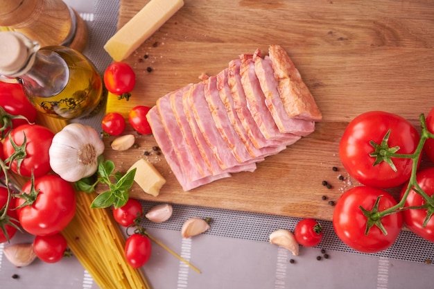 Gesneden pancetta-hamspek op houten snijplank bij binnenlandse keuken