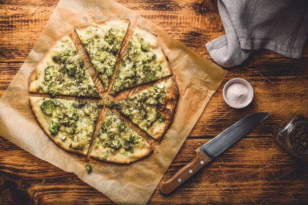 Gesneden pizza met broccolikruiden en parmezaanse kaas