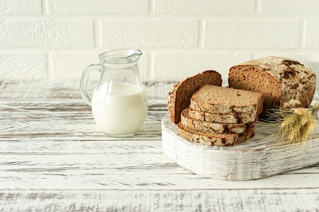 Gesneden roggebrood op houten snijplank naast kruik met melk. lekker eten close-up. zelfgebakken brood.