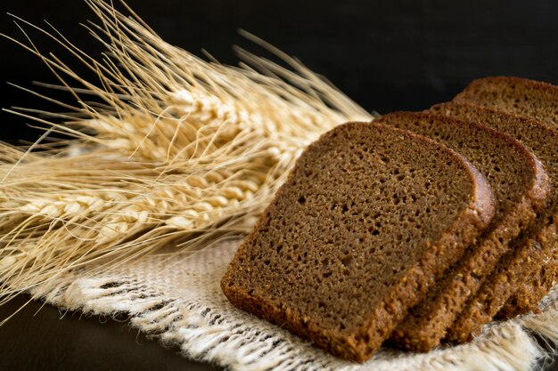 Gesneden roggebrood op zwarte achtergrond met oren.