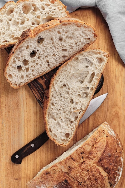 Gesneden rond rustiek brood zonder te kneden op een snijplank naast een mes zelfgemaakte volkoren broodlay-out op het verticale frame van de tafel