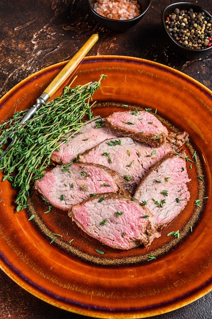 Foto gesneden rosbief entrecote mals biefstuk op een rustieke plaat. donkere achtergrond.