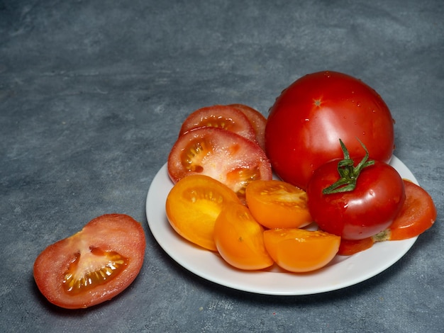 Gesneden sappige tomaten van verschillende variëteiten op een bord Broeikasgassen oranje tomaten Gezonde voeding Stilleven van groenten