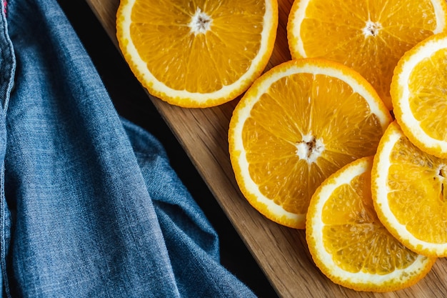 Gesneden sinaasappelfruit in de buurt van denimtextiel op een houten bord Oranje sappig fruit citrus minimaal concept