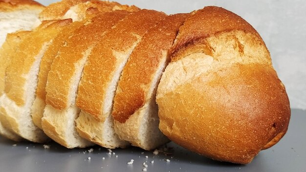 Gesneden tarwebloem Smakelijke sneetjes wit broodje met krokant gebakken korst Product met gluten Vers brood Grijze achtergrond Kruimels op tafel