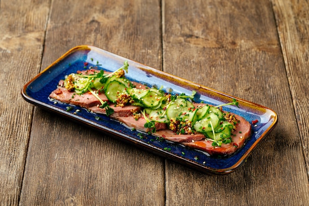 Gesneden tataki rosbief tong met zeewier chuka op het houten oppervlak