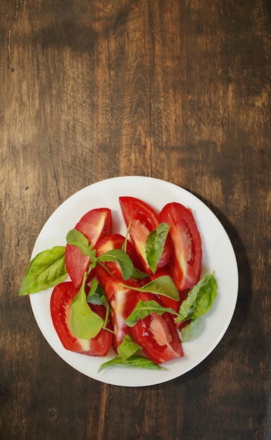 Gesneden tomaten met sla op een witte plaat