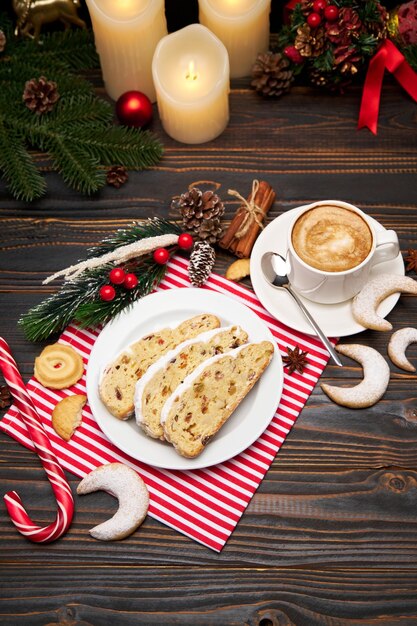 Gesneden traditionele kerststolcake met marsepein en nieuwjaarsversieringen op houten achtergrond
