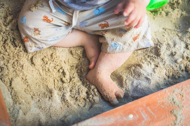 Gesneden uit jonge babyjongen die in de zandbakbenen speelt