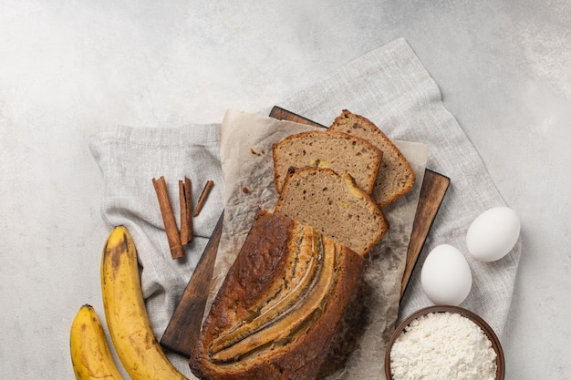 Gesneden vers bananenbrood met ingrediënten op lichte achtergrond