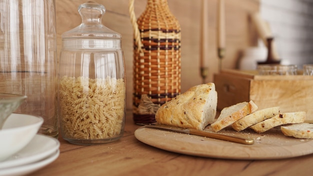 Gesneden wit brood op een houten dienblad. moderne keuken in scandinavische stijl. pasta in een glazen pot